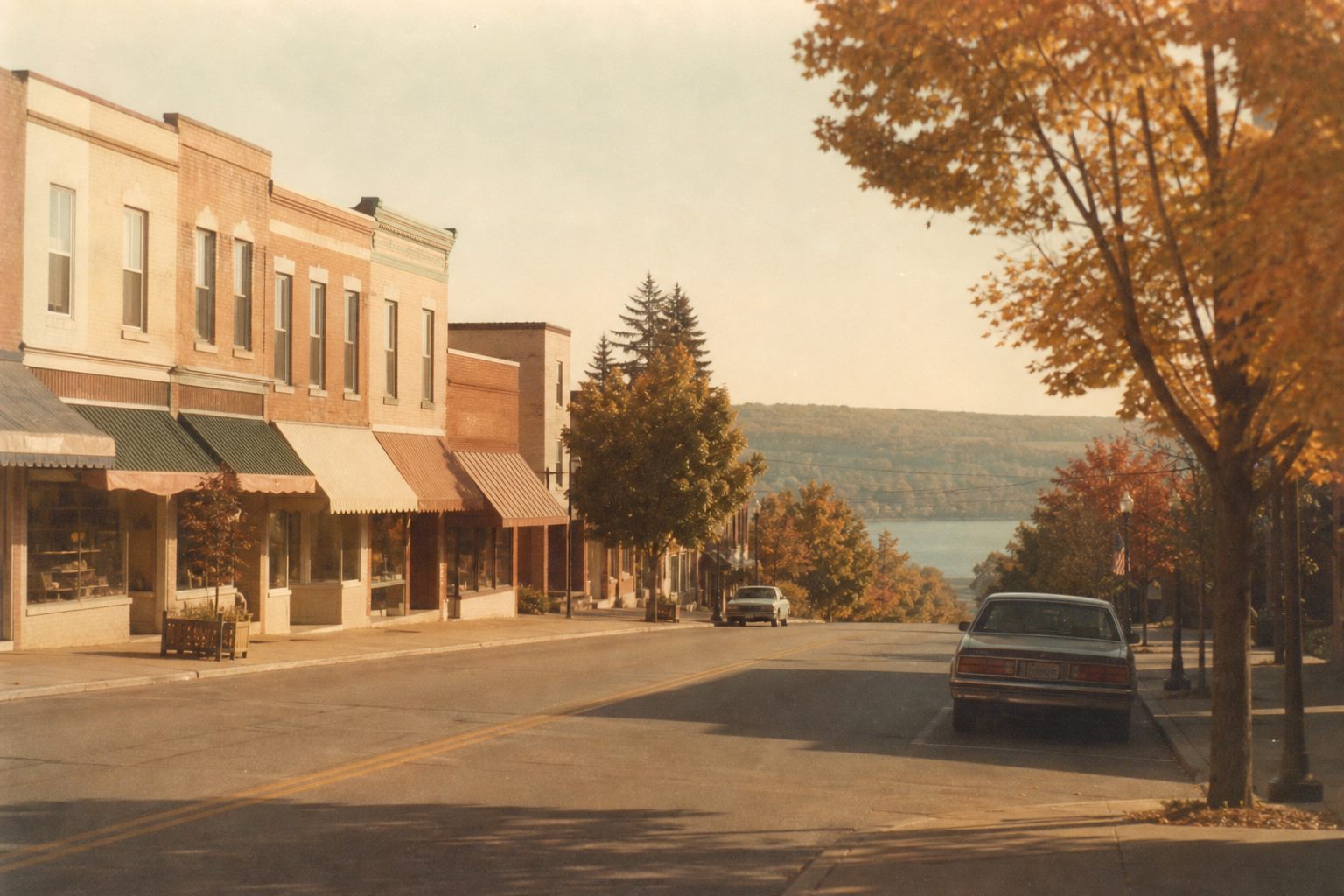 Quiet Lewiston street with low brick storefronts and maples turning gold in early autumn